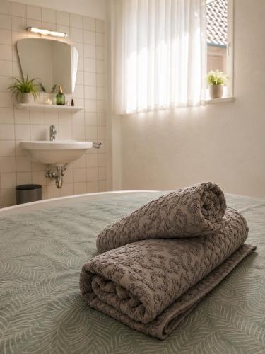 a bed with two towels on it with a sink at Guesthouse - Weeze Rooms in Weeze
