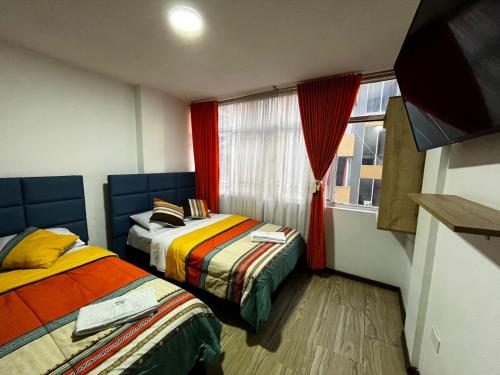 two beds in a room with a window at Hotel Inkanta in Ipiales