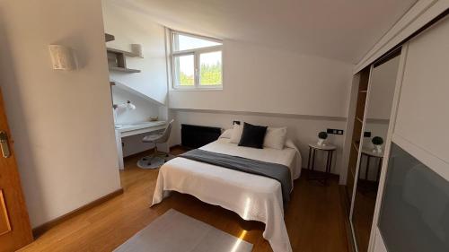 a bedroom with a bed and a desk and a window at Villa Romeo in Oviedo