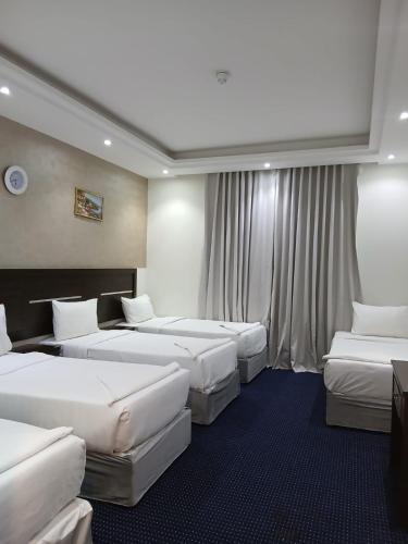 a hotel room with four beds and curtains at فندق نمبر وان 3 in Al Masfalah