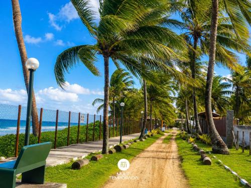 a dirt road next to the beach with palm trees at Casa Ilha do Sol - Vera Cruz/BA in Vera Cruz de Itaparica