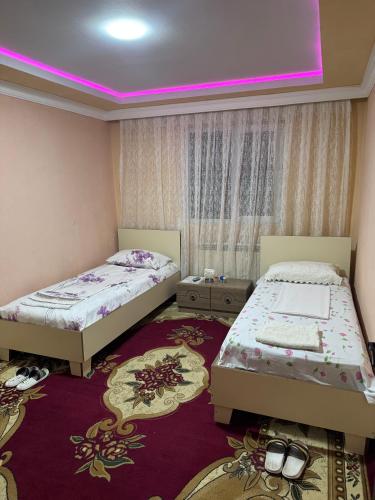two beds in a room with a pink lighting at Elit Hotel in Mingachevir