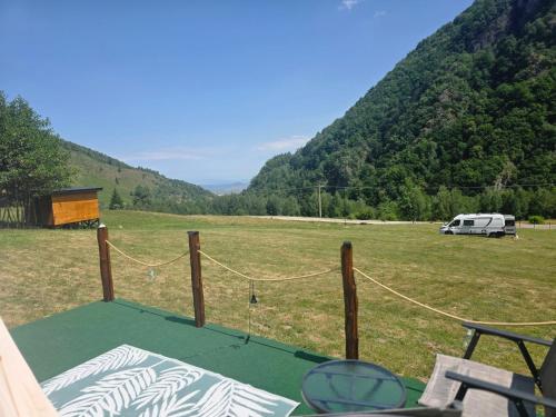a view of a field with a rv in the background at Camping Inima Retezatului in Nucşoara