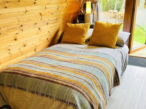 a bed in a room with a wooden wall at Brora Escapes in Brora