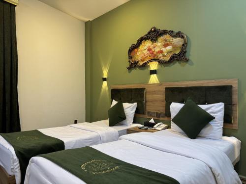 two beds in a room with green walls at Modern Palace Hotel in Al Fayşalīyah