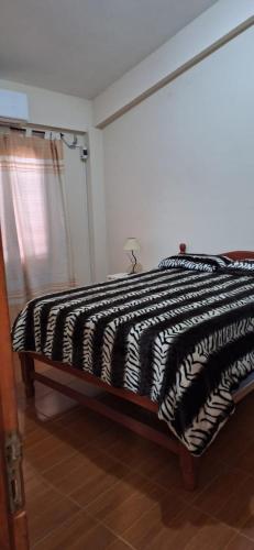 a bed with a black and white comforter in a room at Ciudad de Nieva a pasos de Ciudad Cultural in San Salvador de Jujuy