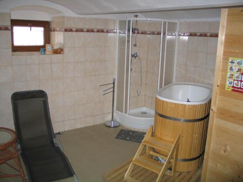 a bathroom with a tub and a chair and a shower at Penzion u Antošů in Jeseník