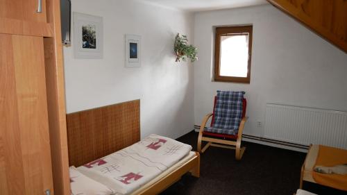 a small room with a bed and a chair at Penzion u Antošů in Jeseník