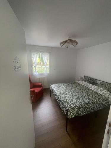 a bedroom with two beds and a red chair at Gîte de la Nolière in La Lande-Saint-Siméon