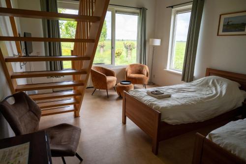 a bedroom with a bunk bed and chairs and a staircase at Boerderij "De Verwondering" in Goudriaan