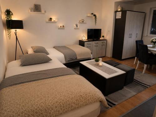 a room with three beds and a table and a tv at Apartman Angela in Foča