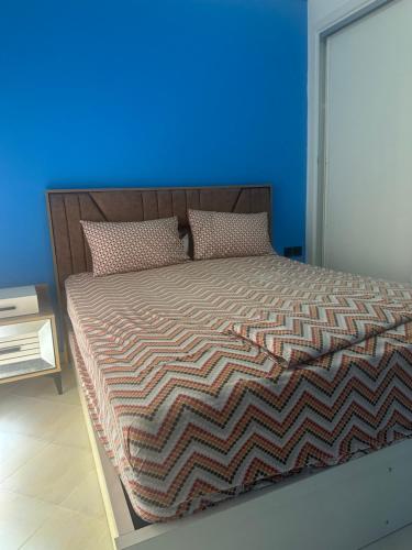 a bedroom with a large bed with a blue wall at Stodio sofia in Essaouira