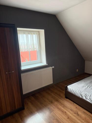 an attic bedroom with a bed and a window at Apartament Piętrowy 138m2 in Gniezno