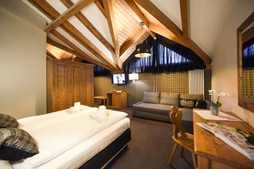 a bedroom with a large bed and a couch at Hotel Orso Grigio in Selva di Cadore
