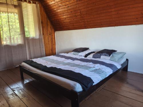 a large bed in a room with a wooden ceiling at Chata Leonard in Farná