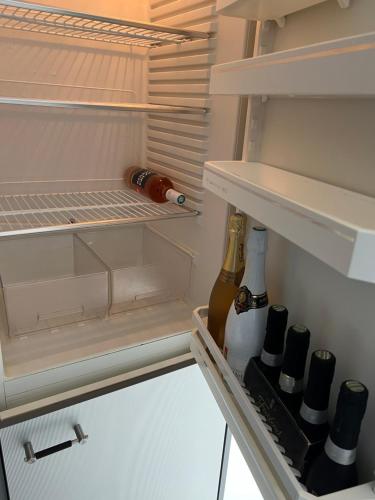 an open refrigerator with wine bottles in it at Wohnung am Heimberg in Churwalden