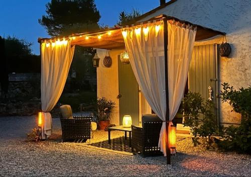 a patio with curtains and a table and chairs at Villa Les Lucioles - Chambre indépendante - Piscine privative - Petit déjeuner - Parking in Valbonne