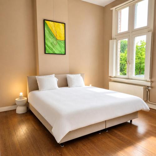 a large white bed in a room with two windows at Spacious manor house with pool & playground in Essen