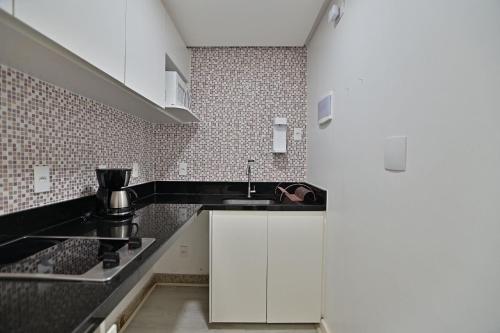 a kitchen with white cabinets and a sink at Flat 337 vista lago no Lake side in Brasília
