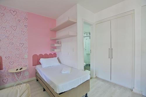 a bedroom with a pink wall with a bed at Flat 337 vista lago no Lake side in Brasília