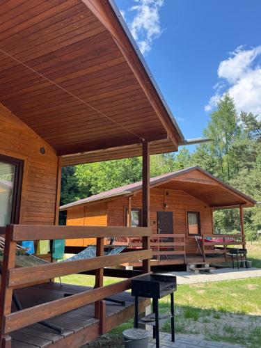 a large wooden cabin with a large deck at Domki Letniskowe Morena in Ostrowo