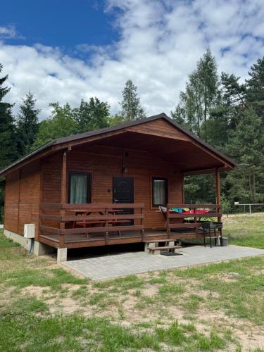 a log cabin with a porch and a picnic table at Domki Letniskowe Morena in Ostrowo