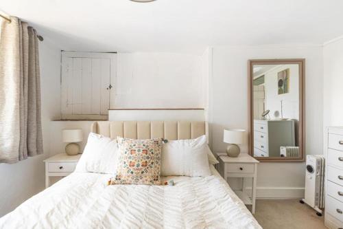 a bedroom with a white bed and a mirror at Beamed Cottage in Broadwindsor, Wood Burner in Broadwindsor