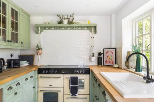 a kitchen with green cabinets and a sink at Beamed Cottage in Broadwindsor, Wood Burner in Broadwindsor