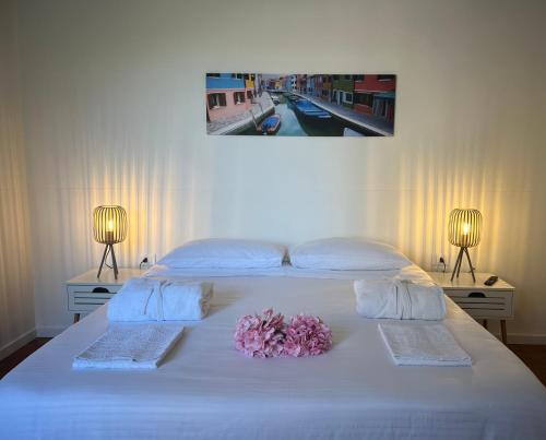 a white bed with a bouquet of flowers on it at Appartamento Sole in Tessera