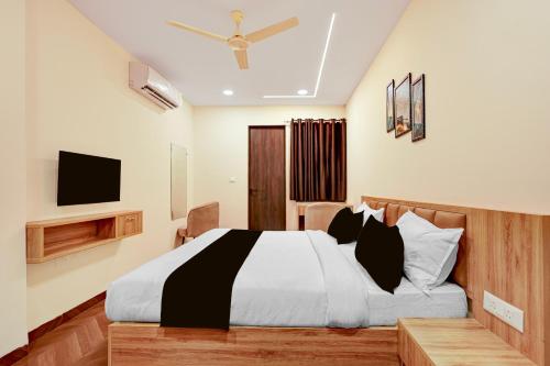 a bedroom with a black and white bed and a tv at Hotel O Grand Shivay in Indore