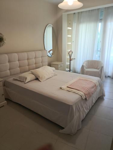 a bedroom with a large white bed and a mirror at Evi's house in Iraklitsa