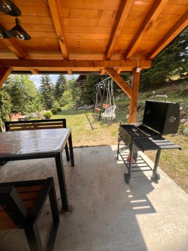 a picnic table with a laptop on it under a wooden roof at Brvnara Tarska Zora in Sekulić 
