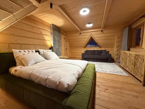 a large bed in a wooden room with a couch at Tatra Whisper Chalet in Ząb
