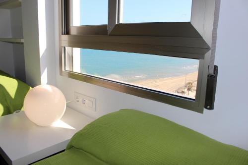 a room with a green couch and a window with the ocean at Apartamentos Guillem in Playa de Miramar