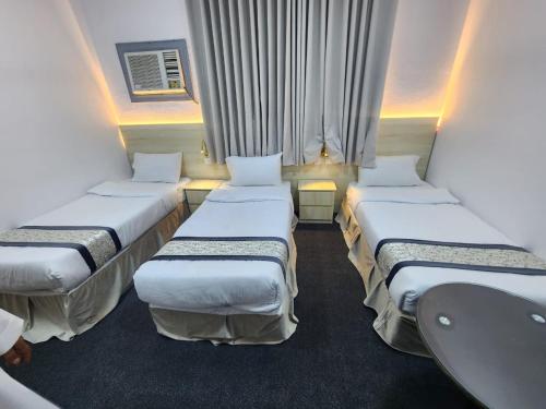 a room with four beds in a room with a window at Rahat Alubur Hotel in Medina