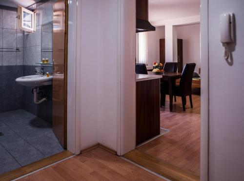 a bathroom with a sink and a kitchen with a table at Modex Apartments in Paraćin
