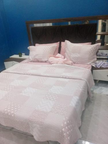 a large bed with pink and white sheets and pillows at Appartement a bir mourad rais in Birmandreis