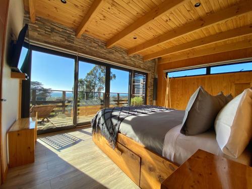a bedroom with a bed and a large window at ONDA DE MAR VILLAS - Solo para Dos - Vistas al Mar - Sesión Hidromasaje Incluida - Quincho - Privacidad in Pichilemu