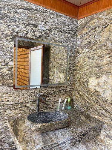 a stone bathroom with a sink and a mirror at Mây Retreat in Nguyên Ngoại