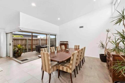 a dining room with a wooden table and chairs at Tomakin Tonic in Tomakin