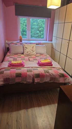 a bedroom with a bed with a blanket and a window at Apartament Tkaczy in Kowary
