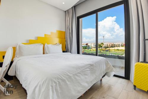 a bedroom with a white bed and a large window at Hotel STAY INN in Agadir