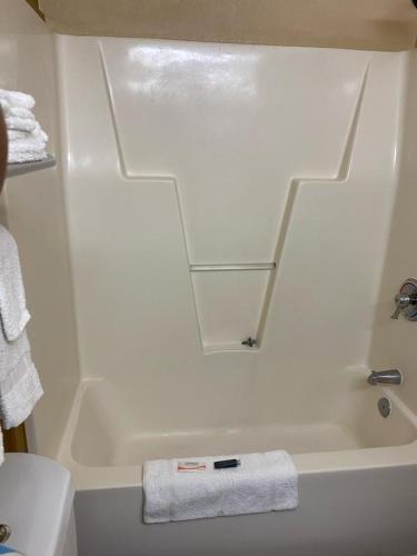 a white bathroom with a tub and a sink at Suburban Studios Winston-Salem near Hanes Mall in Winston-Salem