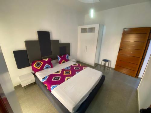 a bedroom with a large bed and a wooden door at Chamber double in Saly Portudal