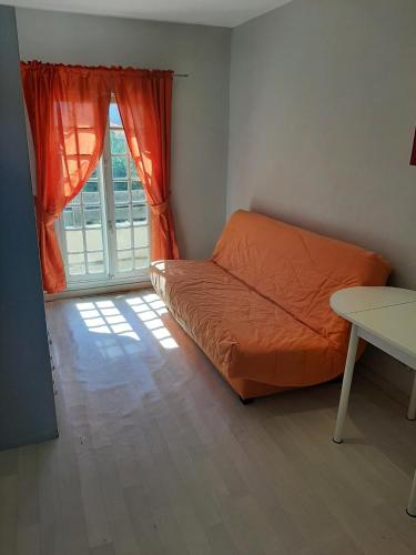 an orange bed in a room with a window at STUDIO VALRAS Plage in Valras-Plage