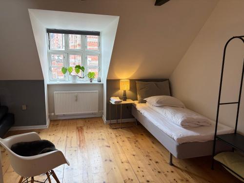 a bedroom with a bed and a chair and a window at Huset ved springvandet in Randers