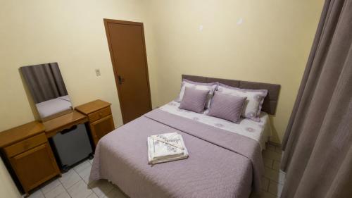 a bedroom with a bed with purple sheets and a television at Casa no Centro Vilhena in Vilhena