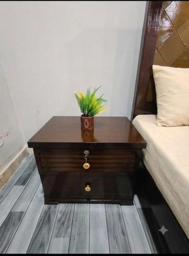 a wooden table with a plant on it next to a bed at AZH Hotel & Rooms in Islamabad