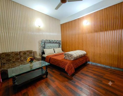 a bedroom with a bed and a couch and a table at AZH Hotel & Rooms in Islamabad