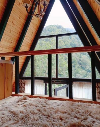 a large window in a log cabin with a large rug at Kaçkin House ayder in Çamlıhemşin